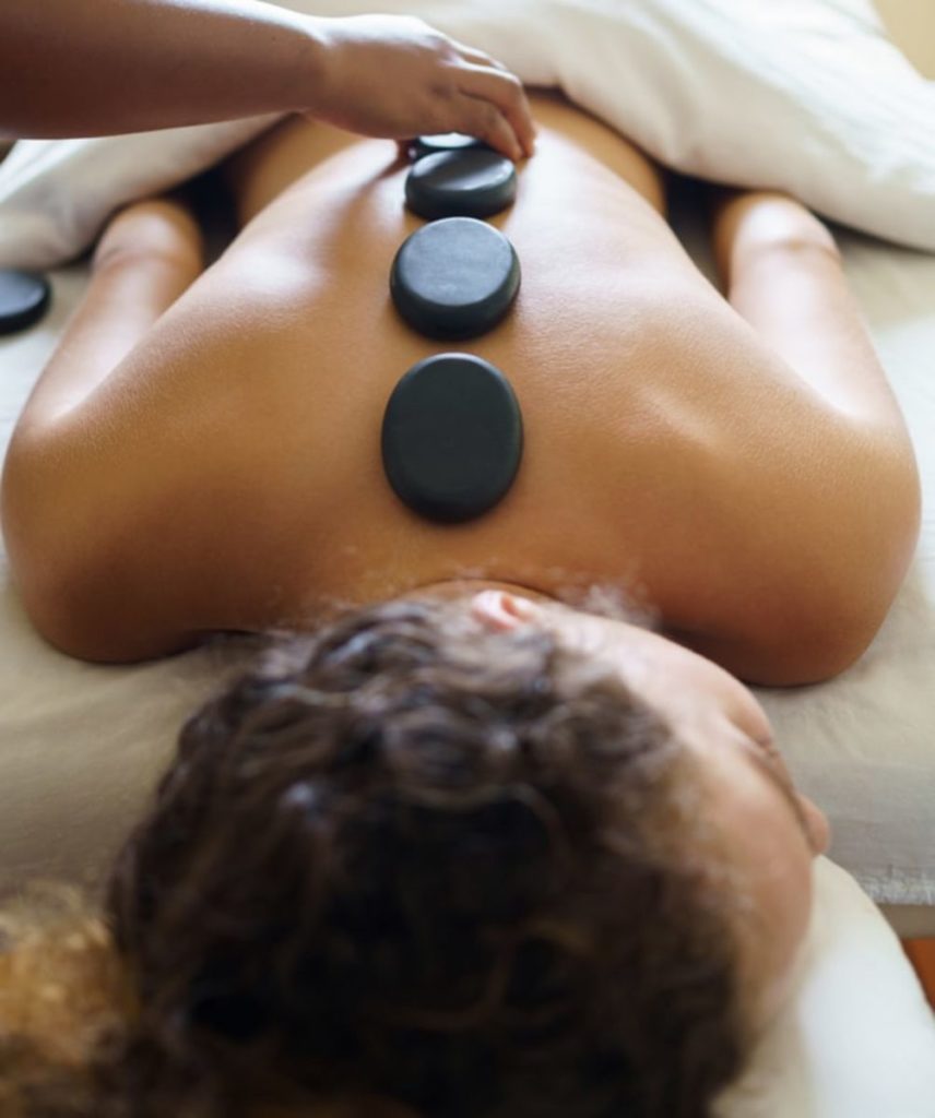 Masaje con rocas en la espalda de una mujer durante un servicio de spa en Rentyl Resorts orlando