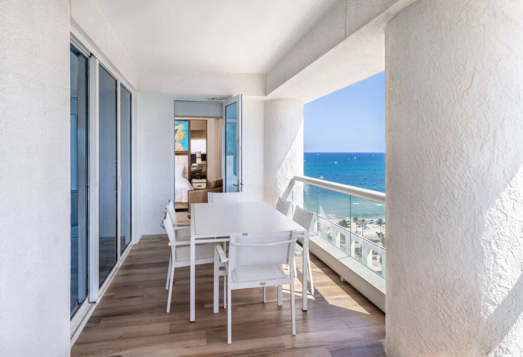 Balcón cubierto de residencia de 2 habitaciones con mesa de comedor y vista intracostera/mar.