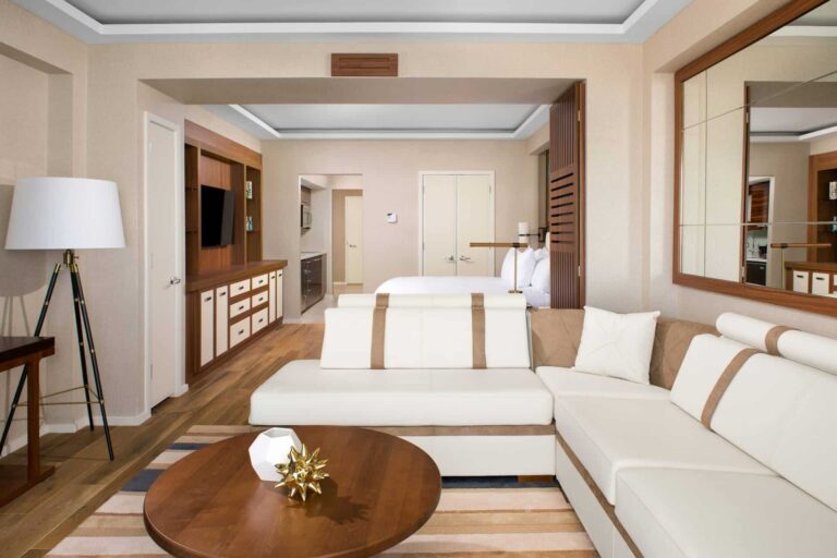 Junior Suite con sofá cama seccional, mesa de centro y televisor montado en la pared.