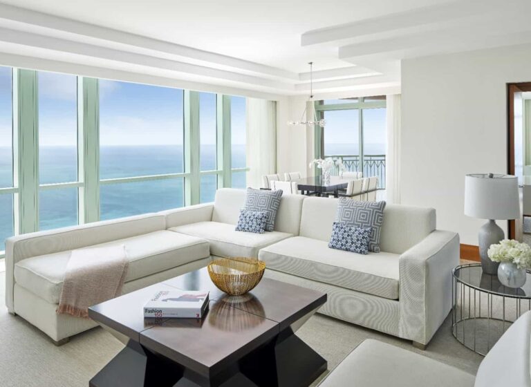 Sala de estar de la suite Sapphire con sofá seccional y vista al mar