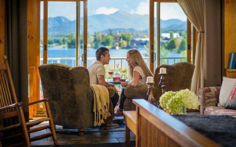 زوجان يجلسان في غرفة الجلوس المشمسة في Cedar Run Room مع إطلالة على البحيرة