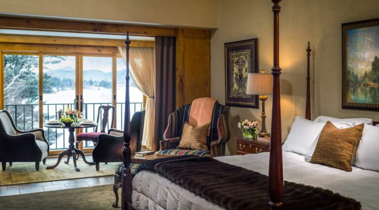 Great Range Room with four poster bed, armchair, and sunroom sitting area overlooking the lake
