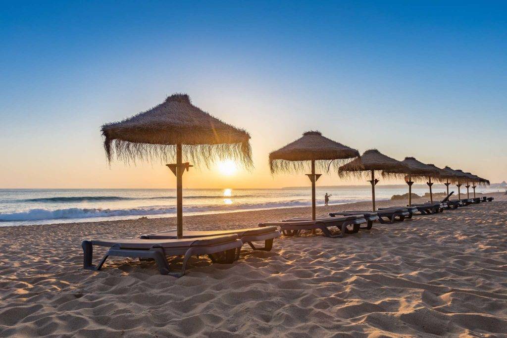 Sonnenschirme am Strand von Salgados bei Sonnenuntergang