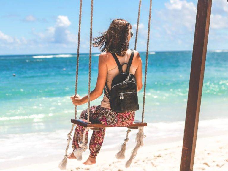 Woman sitting on a swing on a beach