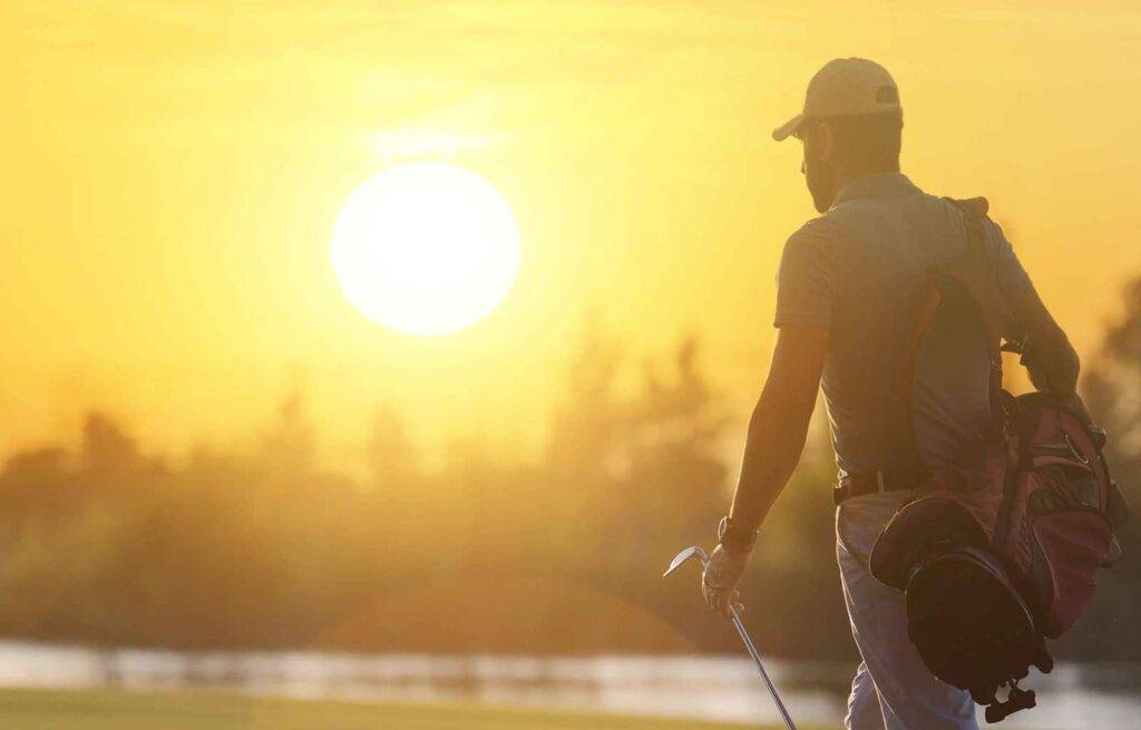 Golfista viendo la puesta de sol sobre un campo de golf
