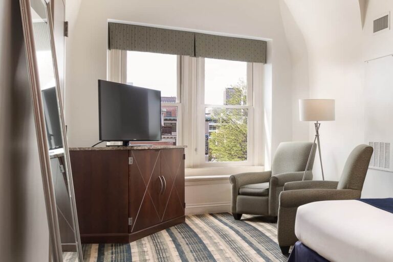 Gran dormitorio en The Mansion en Delaware Avenue con TV, sillón y ventanas.