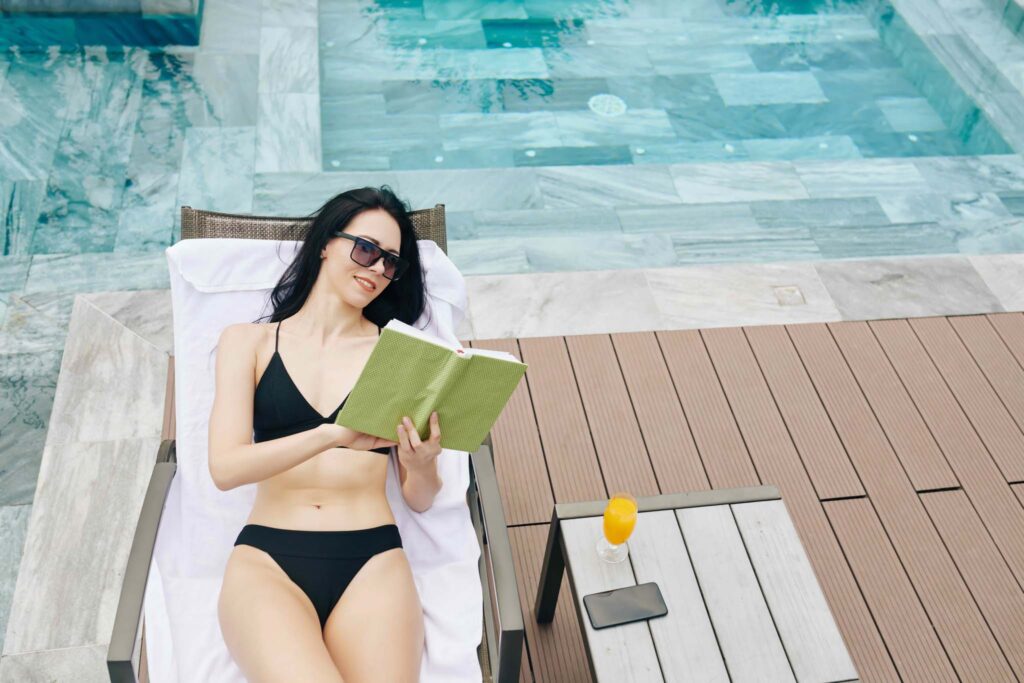 امرأة تقرأ بجوار حمام السباحة.