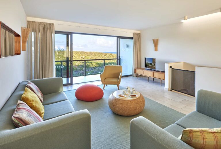 Bay House living room with sofas, TV, and balcony access