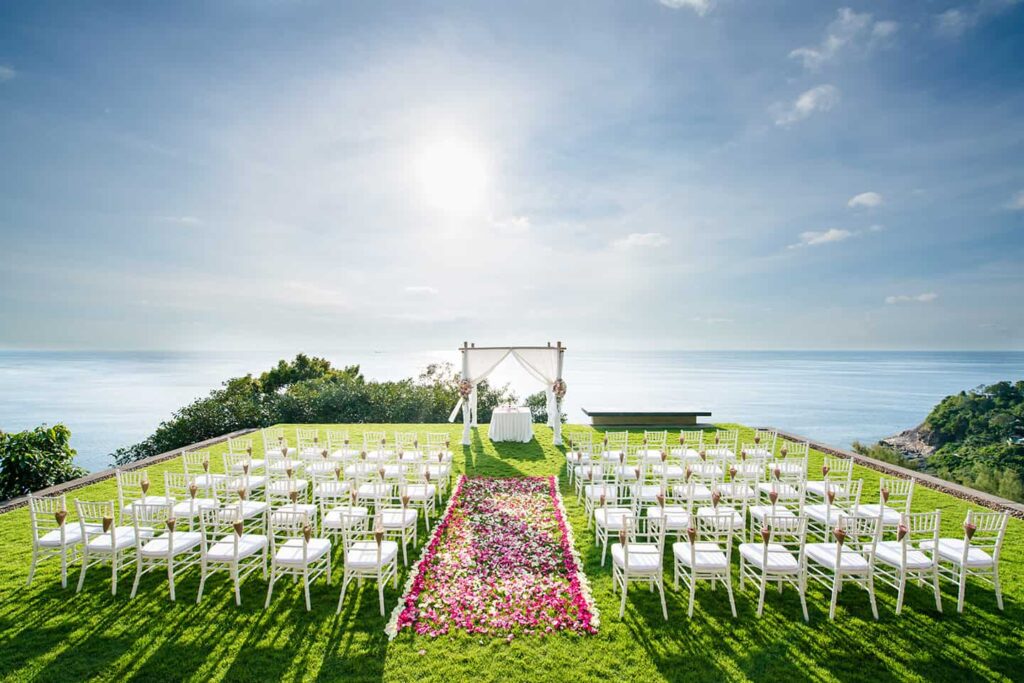 Wedding arch, chairs, and center aisle of flower petals overlooking the water at Paresa Resort