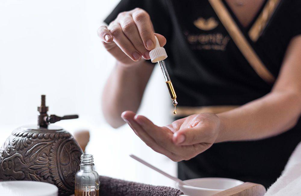 Massage therapist putting oil in hands at Pine Cliffs Resort Spa