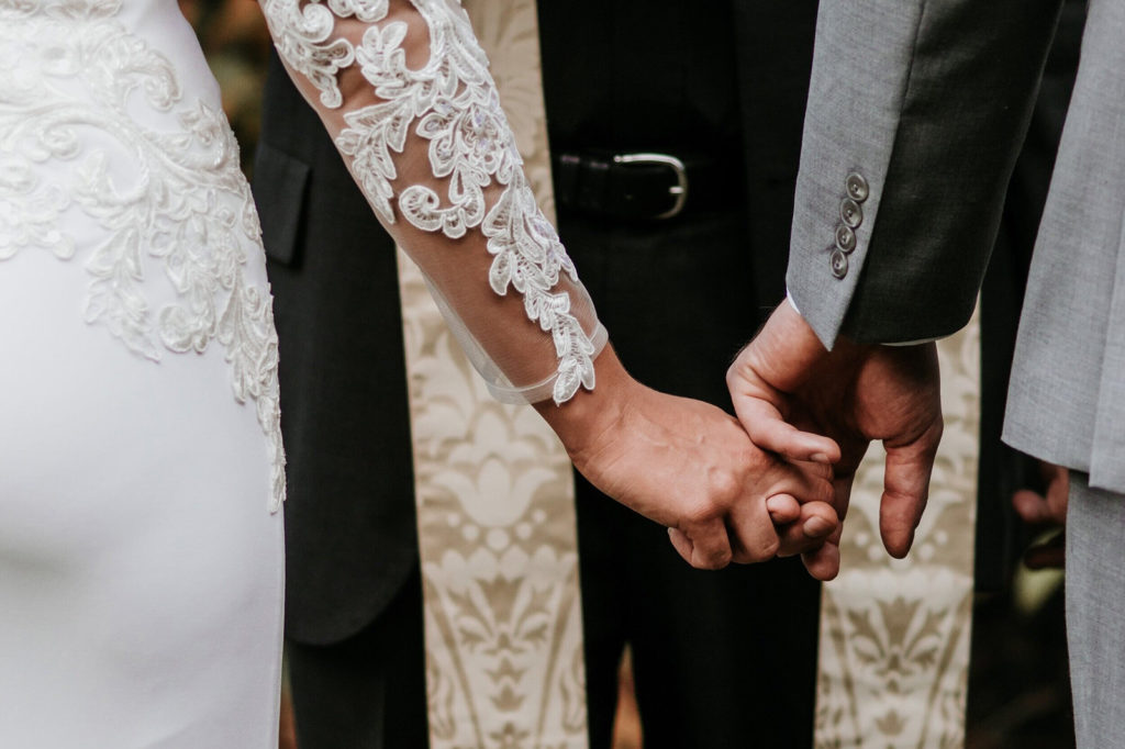La novia y el novio tomados de la mano durante su boda.
