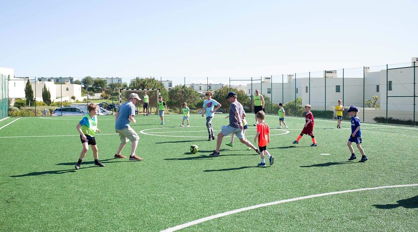 Group of kids and parents playing football (soccer) on the Martinhal Sagres field