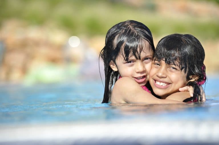 Little girls hugging each other in a pool