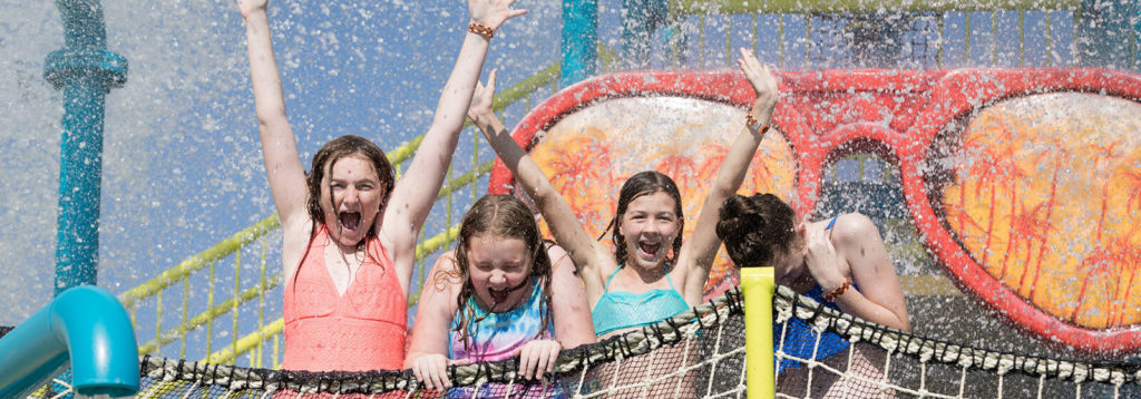 Kids cheer under a big water bucket splashing water on them at Encore Resort at Reunion’s water park.