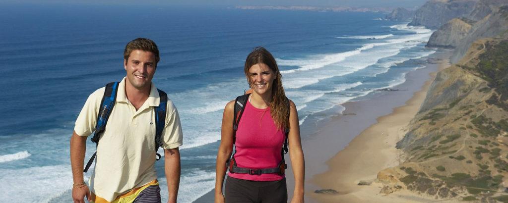 युगल समुद्र तट के बगल में लंबी पैदल यात्रा कर रहे हैं