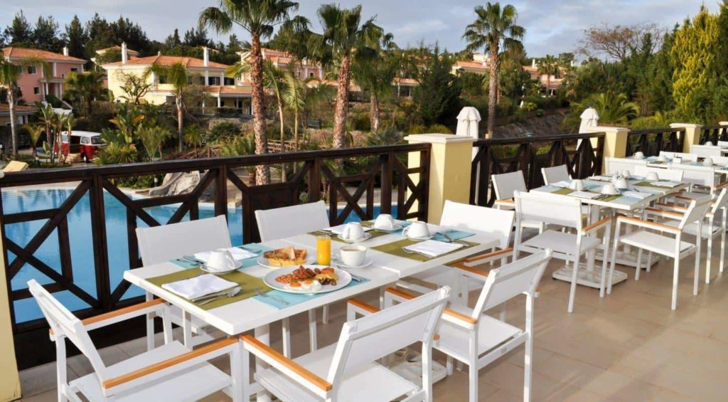 Outdoor tables and chairs on a terrace, overlooking a pool