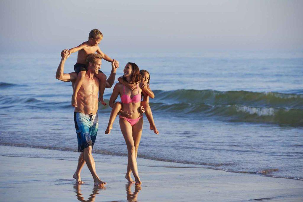 Familia de cuatro personas caminando por la playa