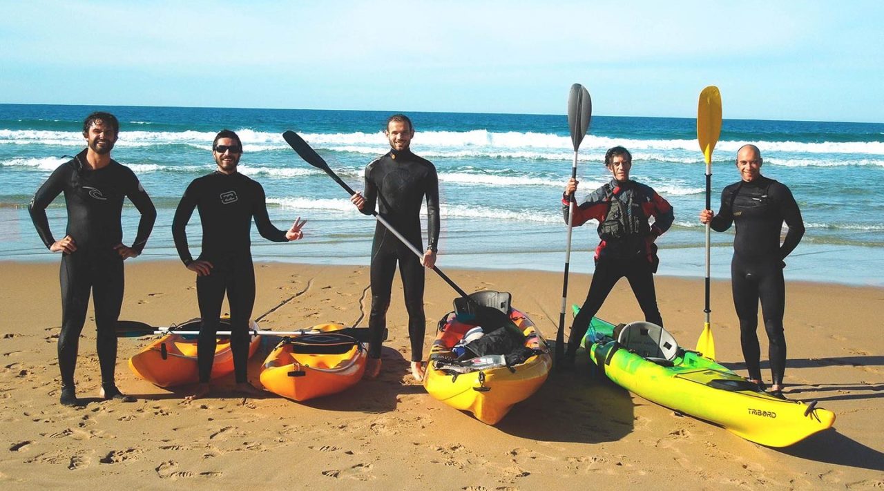 Tour group standing with kayaks on the beach