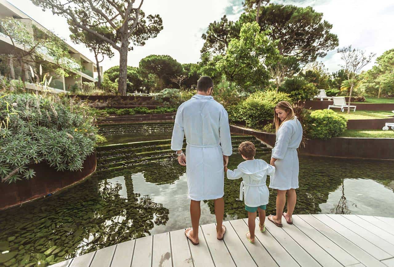Family in bathrobes looking at a water feature