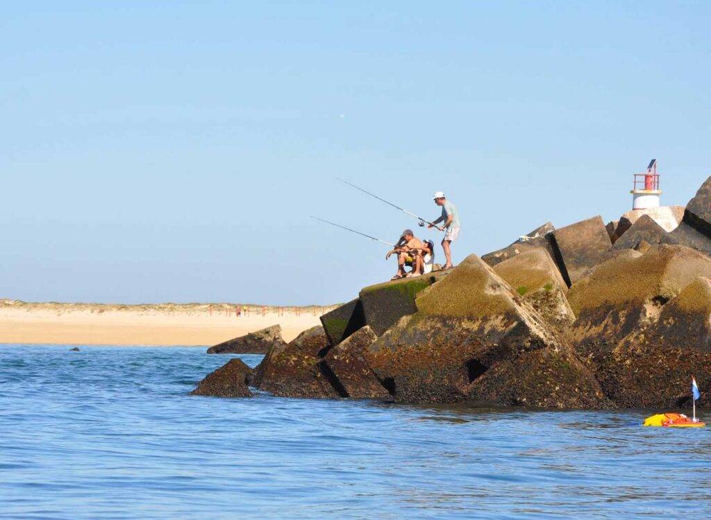 Small group of people fishing in the ocean in Algrave, Portugal