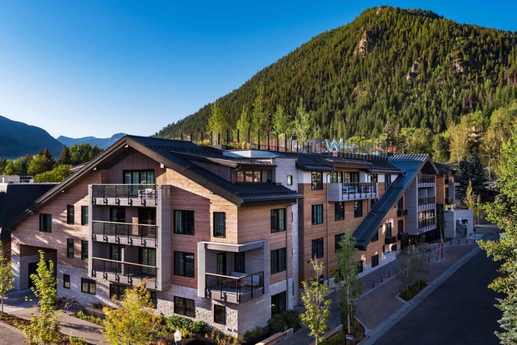 The Sky Residences at W Aspen surrounded by lush green mountains.