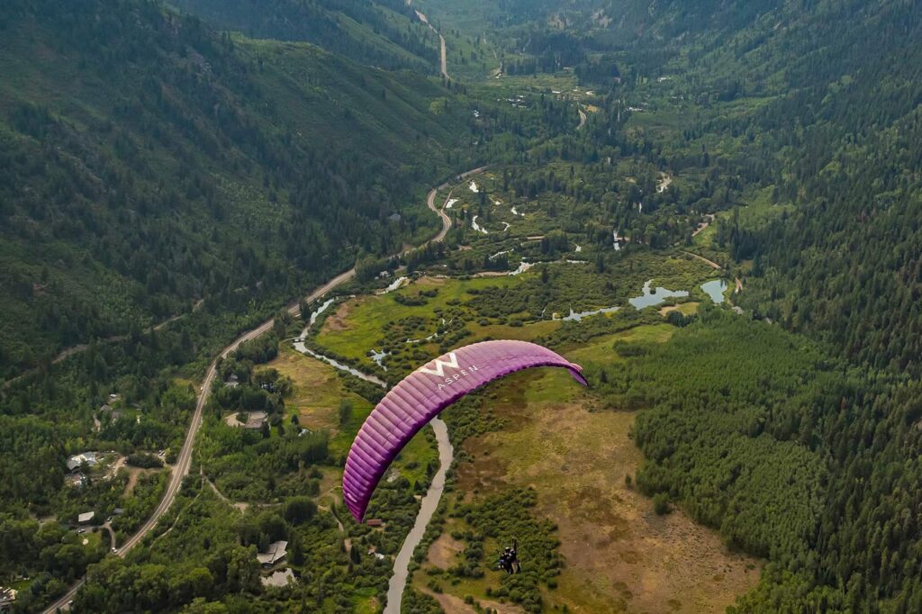 Paraglider flying over valley in Aspen