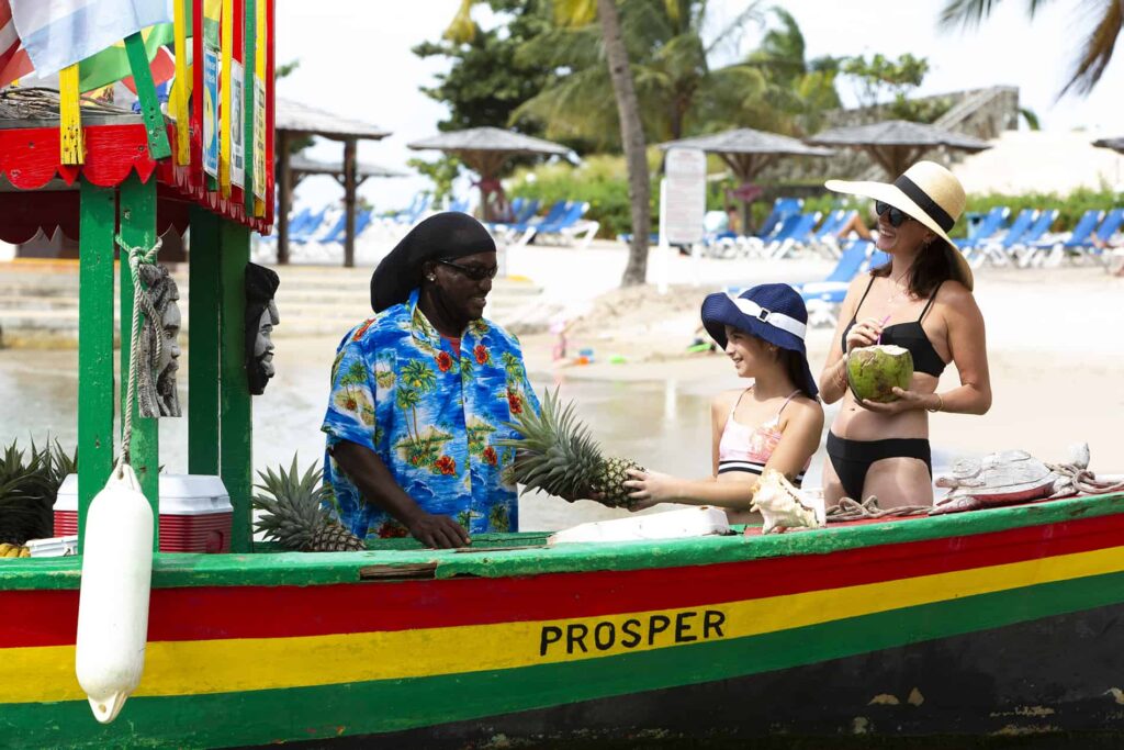 Mother and daughter buying a pineapple from a beach vendor at Windjammer Landing