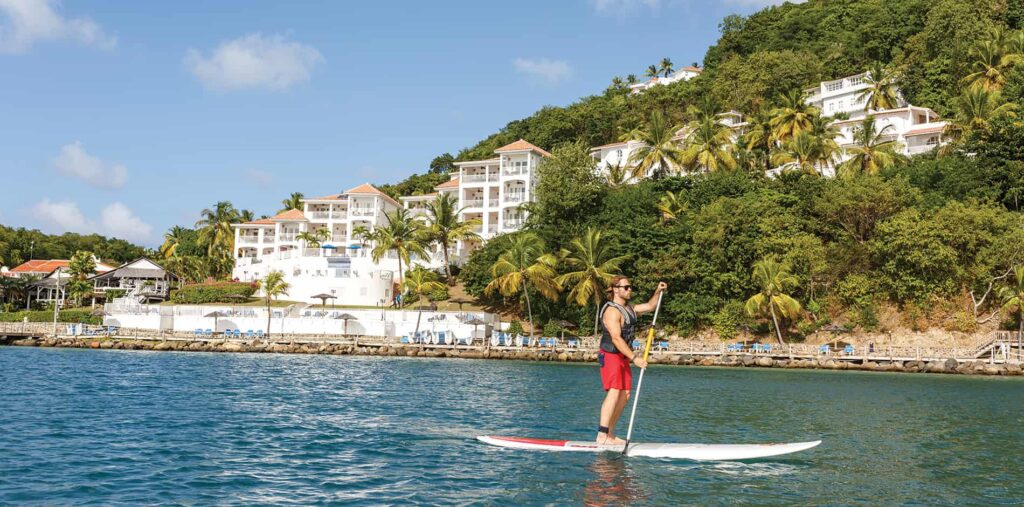 Man paddleboarding in the water in front of Windjammer Landing villas