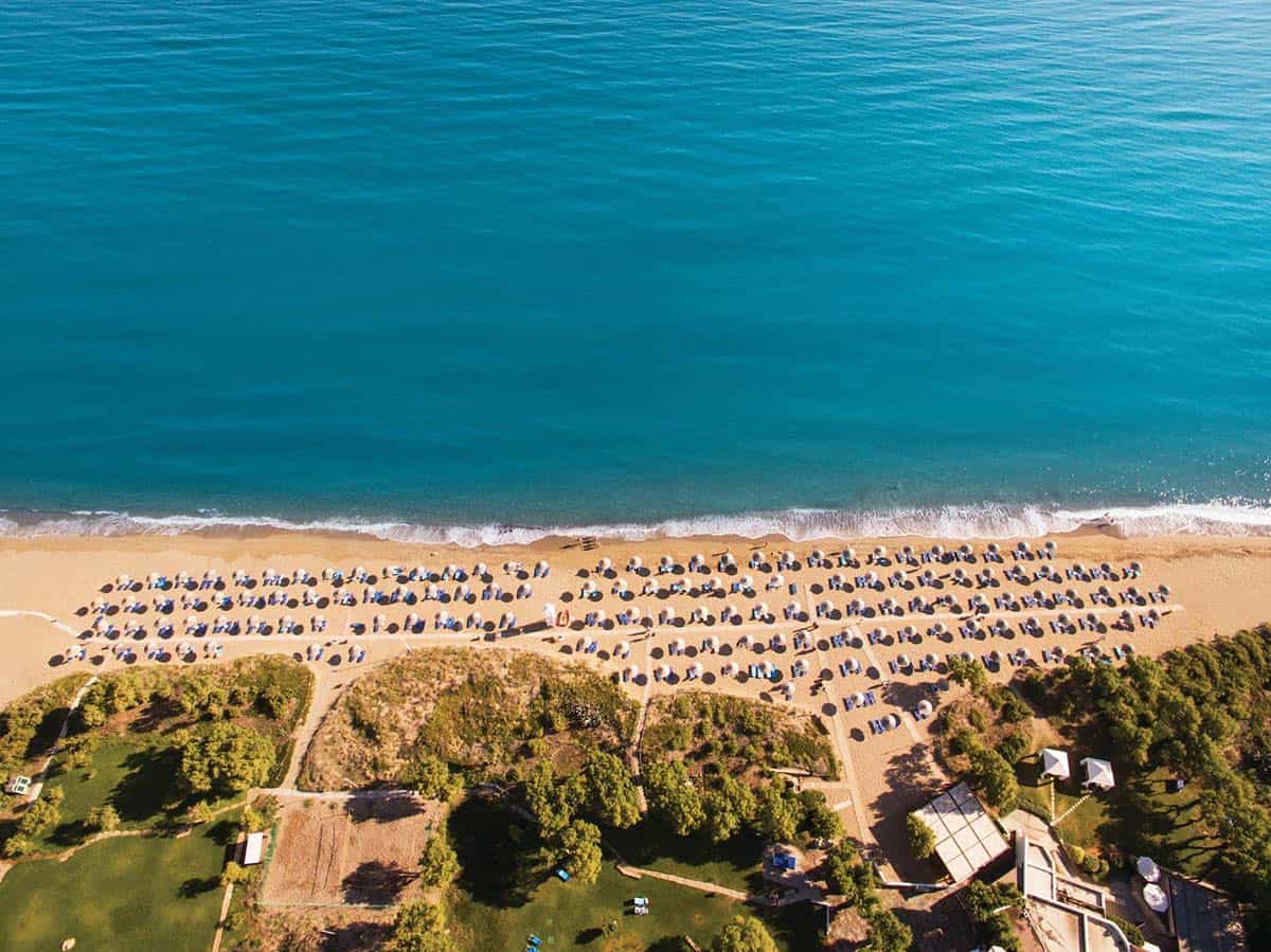 Private beach with lounge chairs and umbrellas at the Agapi Beach Resort