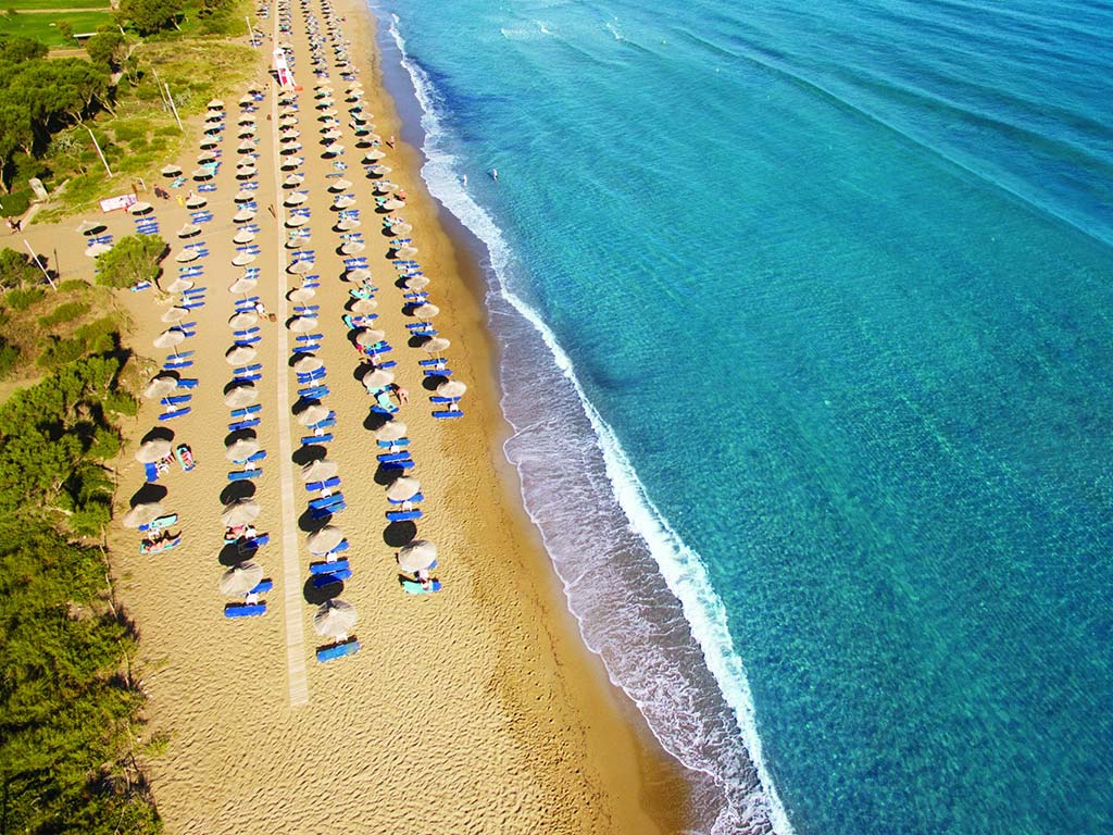 Private beach with lounge chairs and umbrellas at the Agapi Beach Resort