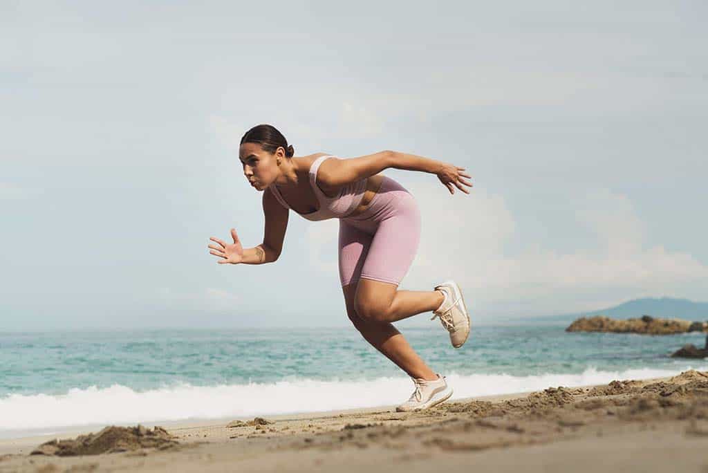 Mujer corriendo en la playa en Agapi Beach Resort