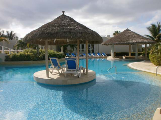 Covered island with lounge chairs in The Atrium Resort pool.