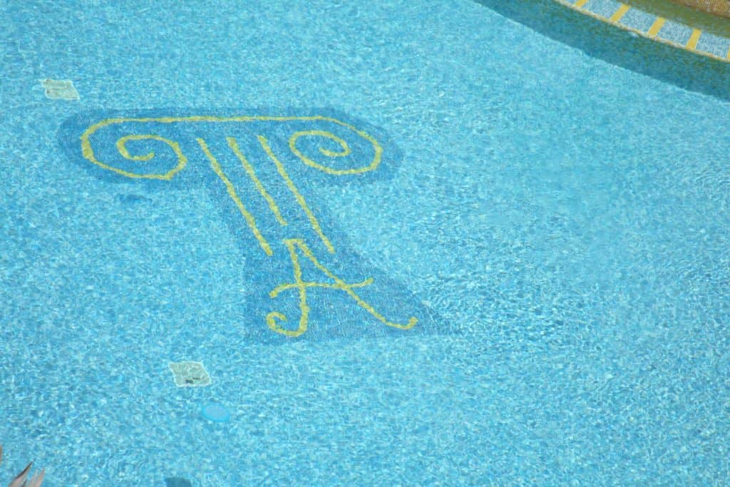 Diseño de azulejos en la piscina del Atrium Resort que representa una columna griega sobre una letra A.