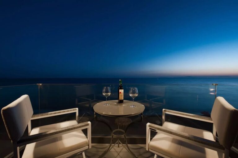 Dexamenes Beachfront Villa balcony overlooking the sea at night with drinks for two.