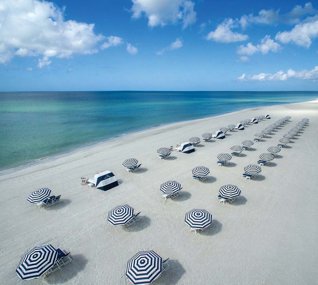 Umbrellas set up on sunny white beach.