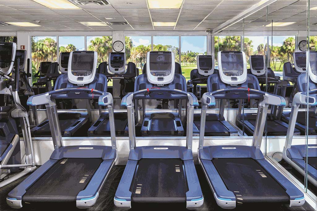 Line of treadmills in fitness center with view of golf course