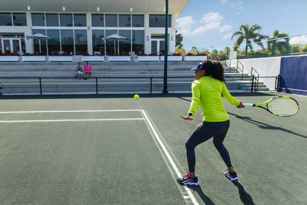 लॉन्गबोट की क्लब टेनिस कोर्ट पर टेनिस खेलती महिला।