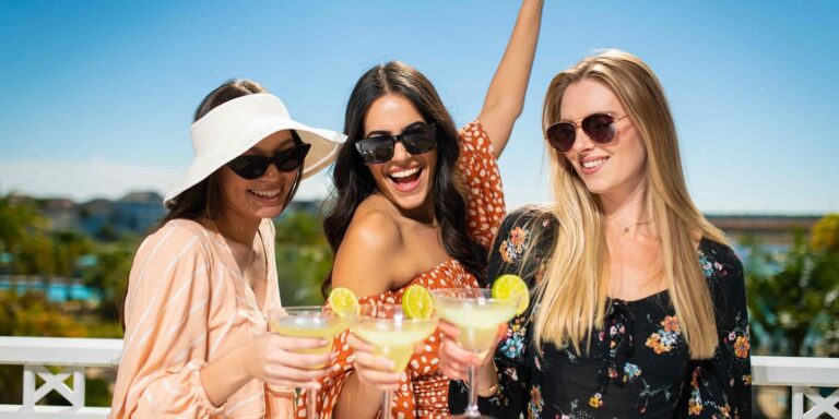 Three women toasting with margarita glasses on a sunny day.