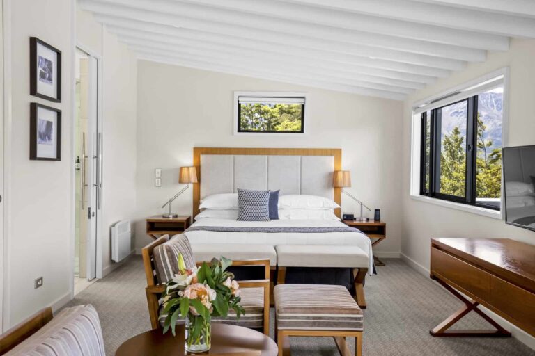 Dormitorio en suite con sillones acolchados y amplio escritorio: Habitación ejecutiva con vista al lago