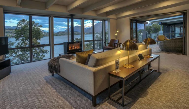 Sala de estar con chimenea, TV y grandes ventanales con vista al lago: Villa de 3 dormitorios con vista al lago