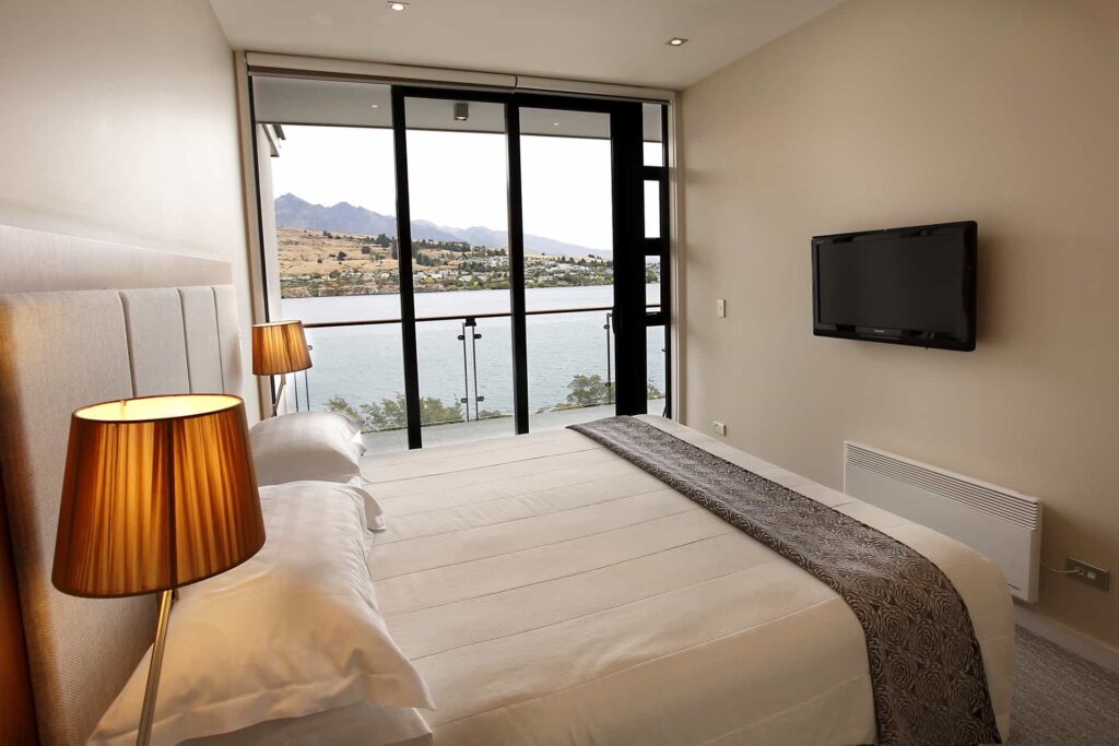 Habitación King en suite con televisor montado en la pared y acceso al balcón: Apartamento con vista al lago
