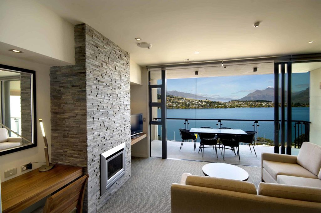 Sala de estar con chimenea y acceso al balcón: Apartamento de 3 dormitorio con vistas al lago