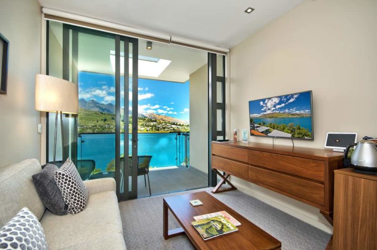 Lake View Hotel Room with sofa, TV, and balcony access