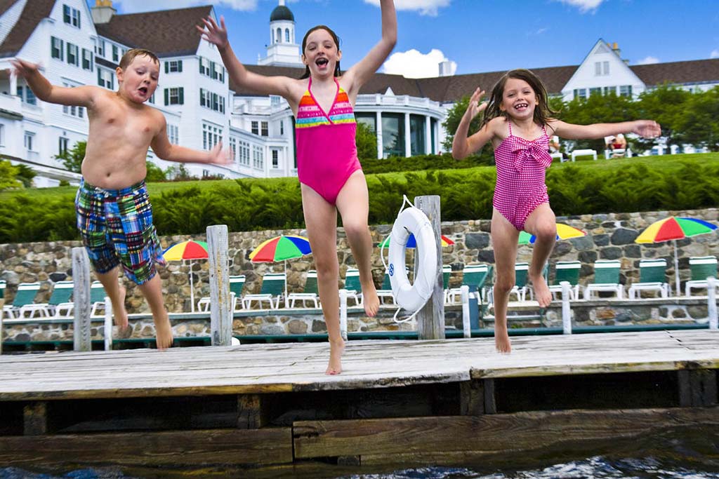 Niños saltando al lago Georgia desde el muelle en The Sagamore Resort.