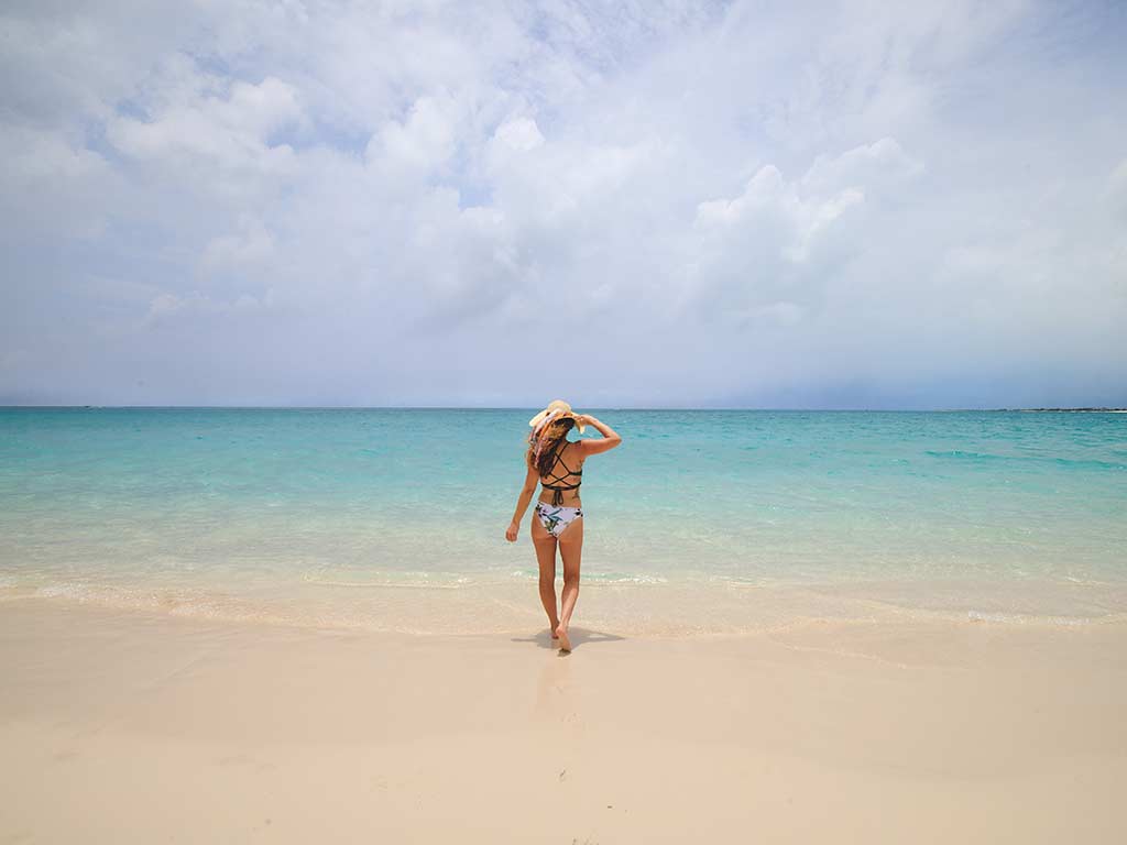 Mujer de pie en una playa mirando el océano.