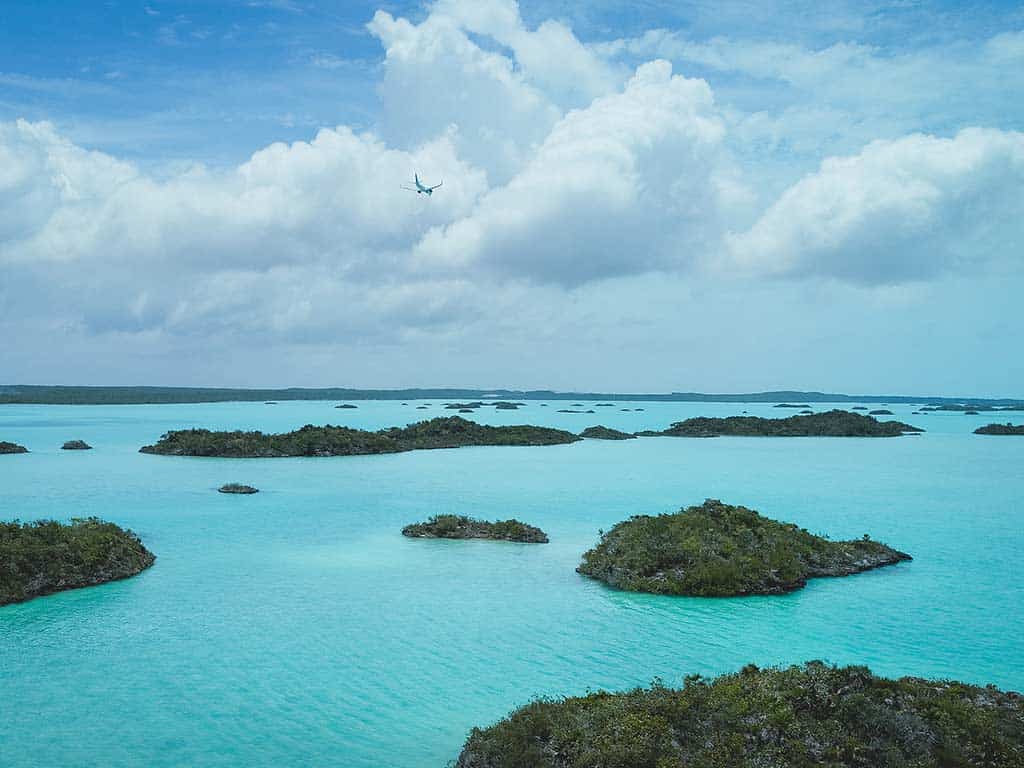 Flugzeug, das über kleine Inseln fliegt, die von blauem Wasser in Turks & Caicos umgeben sind.