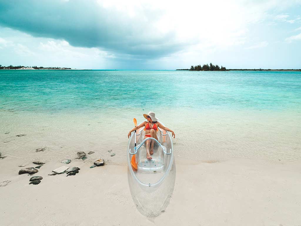 Woman in a transparent kayak on the beach in Turks & Caicos.