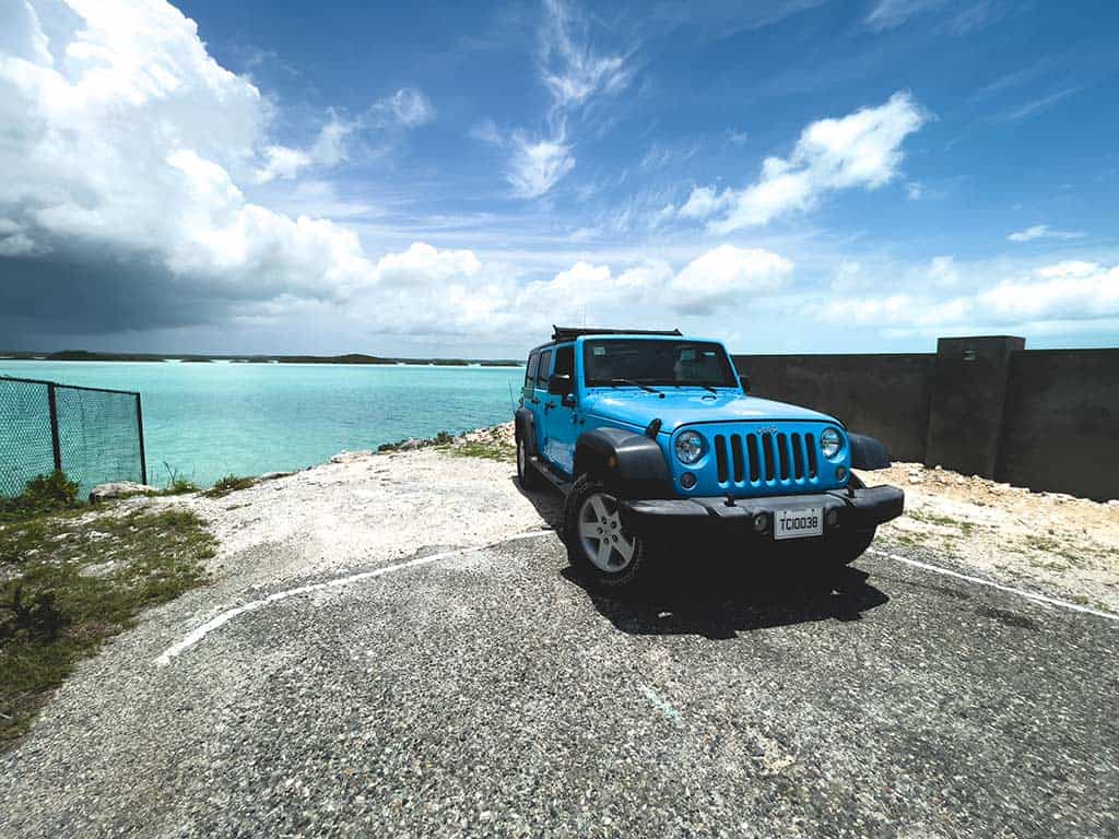 Jeep azul estacionado en una playa oceánica.