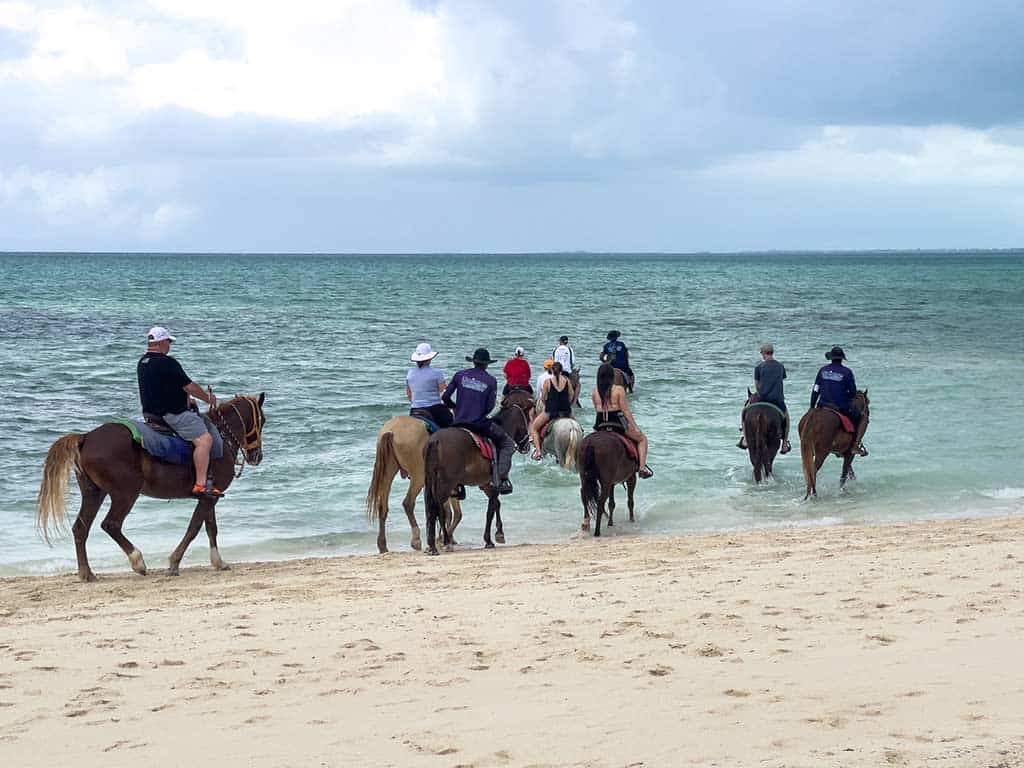 Group of people horseback riding along a beach in Turks & Caicos.