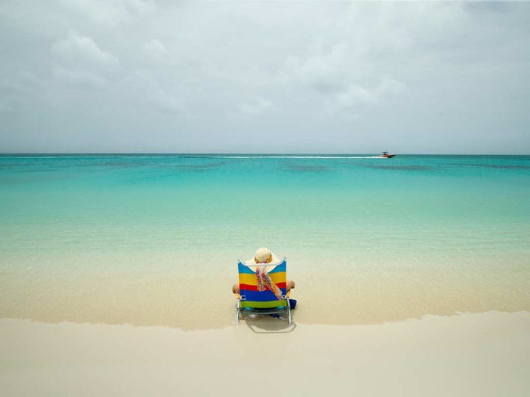 Woman sitting in a lounge chair on the beach.